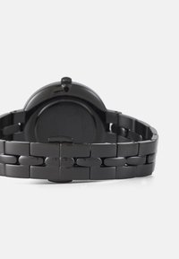 Orologio da polso in metallo nero con cassa liscia e arrotondata e bracciale a maglie. Presenta una finitura lucida e un design minimalista senza marcature visibili.