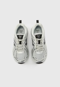 Sølvfargede sportssko med mesh-overdel, svarte detaljer, rund tå og teksturert såle. Har lisser og en løkke bak.