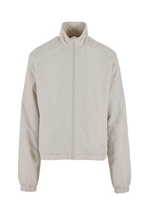 Heledbeez jacket, mille lukuga, elastsete varrukatega ja allääriga. Omab valget äärist õlgadel ja külgedel. Sile kangastekstuuri.