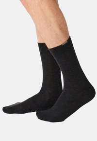 Schwarze Socken aus einer Baumwollmischung mit gerippten Bündchen, Knöchelhöhe und glatter Textur, mit einem dezenten Logo nahe dem Bündchen.