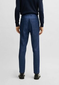 Blue tailored trousers with a textured finish, straight cut, and two back pockets; paired with black shoes.