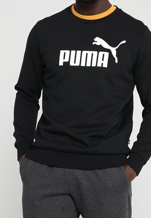 Czarna bluza z długimi rękawami i okrągłym dekoltem, z dużym białym logo "PUMA" oraz białą sylwetką pumy. Miękki materiał, ściągacze na rękawach.