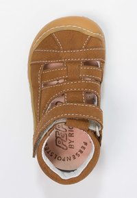 Ruskea nahkasandaali, jossa on useita hihnoja, vaalean beige pohja ja valkoinen ommel. Varustettu pehmustetulla sisäosalla ja merkkipohjallisella.