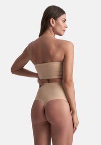 Top bikini bandeau e culotte alta in beige chiaro. Texture liscia, design senza cuciture e stile minimalista senza hardware visibile.