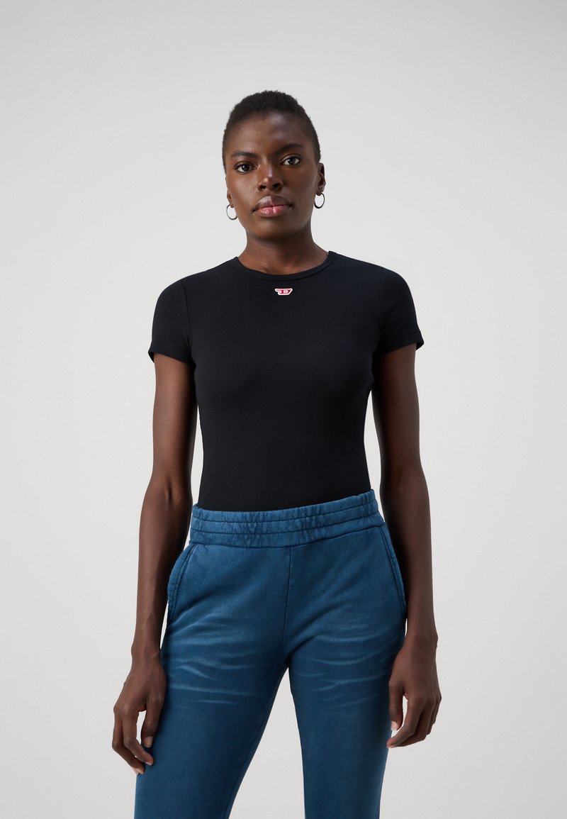 Black fitted t-shirt with short sleeves and a round neckline, featuring a small red logo. Paired with blue elastic waist pants.