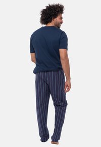 Laivastonsininen puuvillapaita yhdistettynä monivärisiin raidallisiin pyjama-housuihin; housuissa on pystysuorat raidat punaisena, sinisenä ja vihreänä.