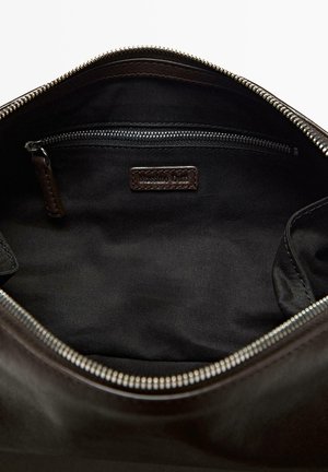 Brown leather bag interior featuring a black fabric lining, a zipper pocket, and a label. The zipper is silver-toned with a smooth finish.