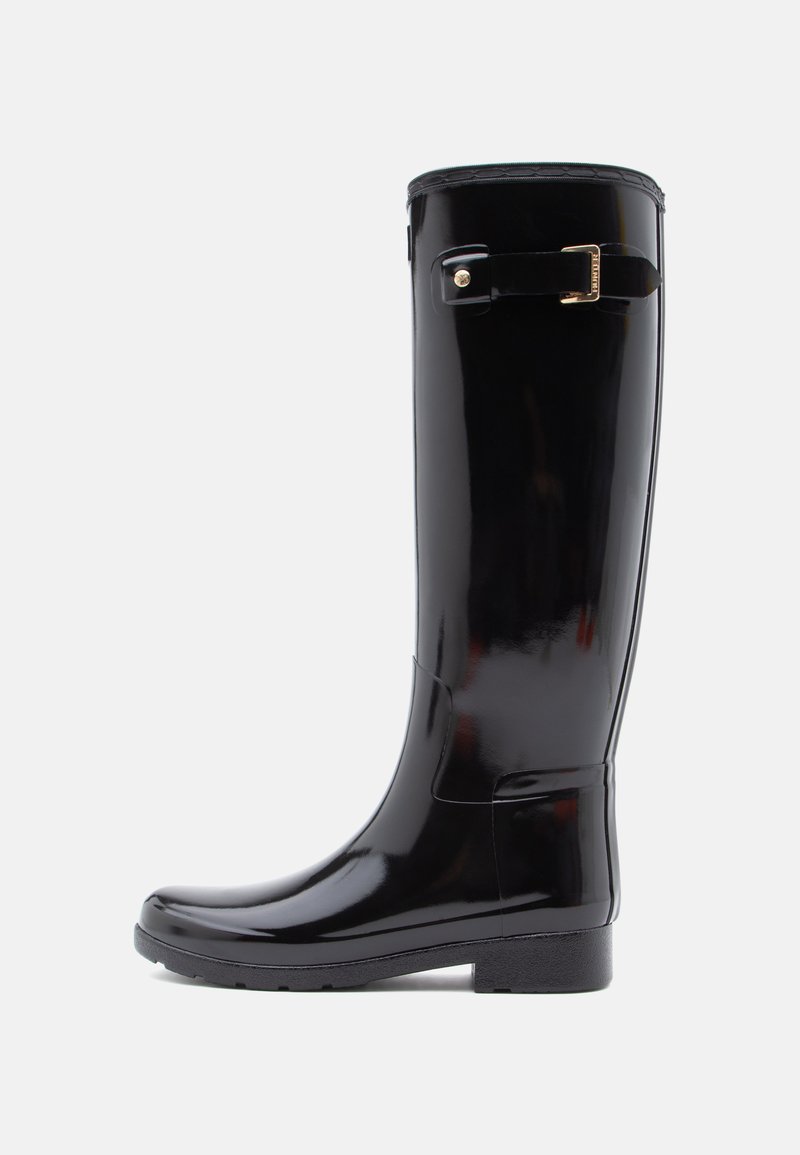 Stivale da pioggia in gomma nera con finitura lucida, design fino al ginocchio e accentuazione in oro sulla parte laterale. Suola piatta con grip testurizzato.