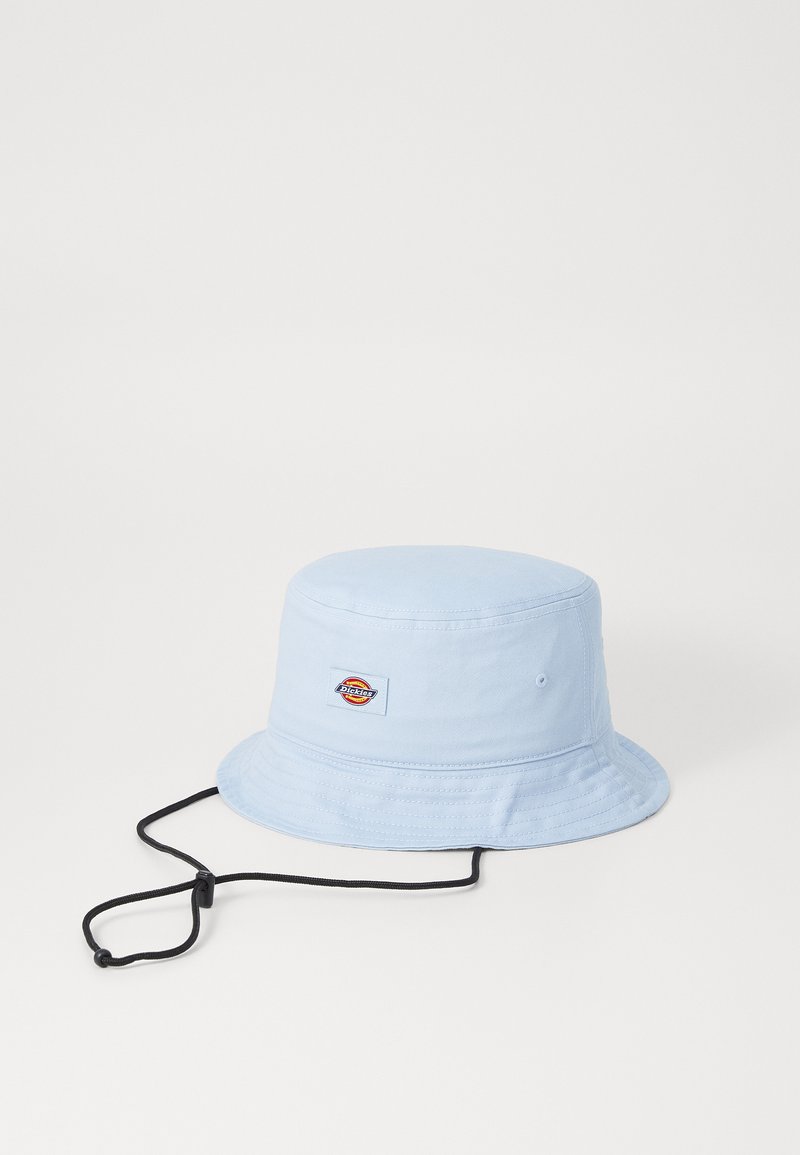 Chapéu de balde azul claro feito de tecido, com uma coroa redonda e uma aba larga e maleável. Correia ajustável preta para o queixo e um patch de logotipo na lateral.