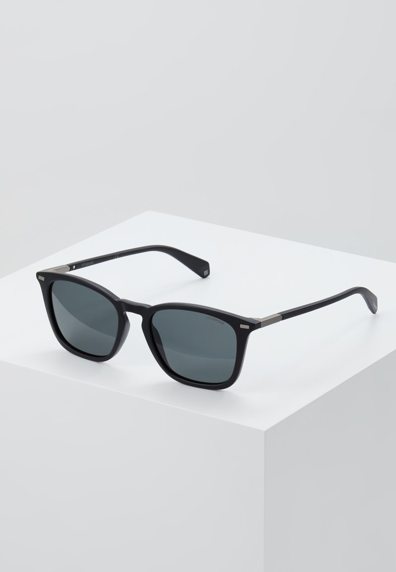 Ochelari de soare rectangulari negri cu lentile gri, având un finisaj mat elegant, accente metalice pe rame și brațe negre robuste.