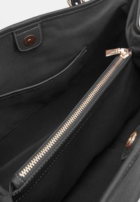 Interno di borsa in tessuto nero con un comparto con zip dotato di accessori in oro rosa, texture liscia e una tasca laterale.