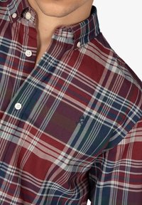 Camisa de cuadros abotonada en rojo, azul marino y verde con cuello. Presenta botones blancos y un pequeño logotipo bordado en el pecho.