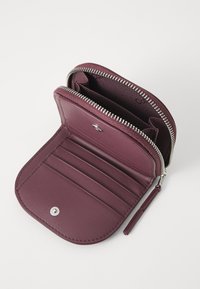 Portfel typu zip w burgundowej skórze z wieloma kieszeniami na karty, gładką teksturą i srebrnym zamkiem błyskawicznym. Kompaktowy i funkcjonalny design.