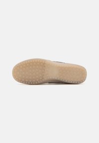 Semelle de chaussure en caoutchouc beige clair avec un motif quadrillé antidérapant, présentée sur un fond blanc uni.