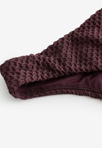 Top de bikini texturizado color malva con un diseño de punto en forma de panal. Cuenta con forro suave y un borde cosido, resaltando la elasticidad del tejido.