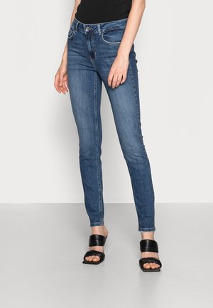 Skinny blue denim jeans with a mid-rise waist, featuring a classic five-pocket design, subtle fading, and stitched detailing on pockets.