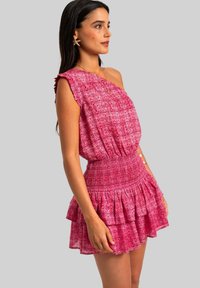Robe florale rose à une épaule avec une taille smockée et un ourlet à volants en cascade ; tissu léger avec un motif texturé et des détails en froufrous.