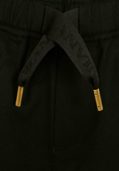 Zwarte broek met een gestructureerde tailleband, voorzien van een zwarte trekkoord met gouden metalen uiteinden. De stof lijkt zacht en glad te zijn.