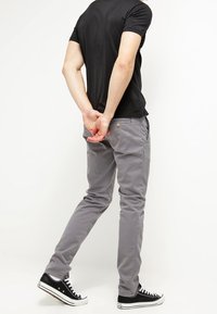 Gray cotton-chambray pants with a slim fit and front pockets, paired with black canvas sneakers and a fitted black t-shirt.