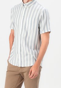 Košile s krátkým rukávem, zapínáním na knoflíky, světle modré a bílé vertikální pruhy, s náprsní kapsou a límečkem.