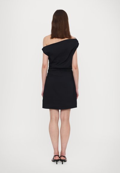 Zwarte off-shoulder jurk met een strakke bovenkant en een rechte zoom. Soepele stof, knie-lengte, gecombineerd met zwarte strappy hakken.