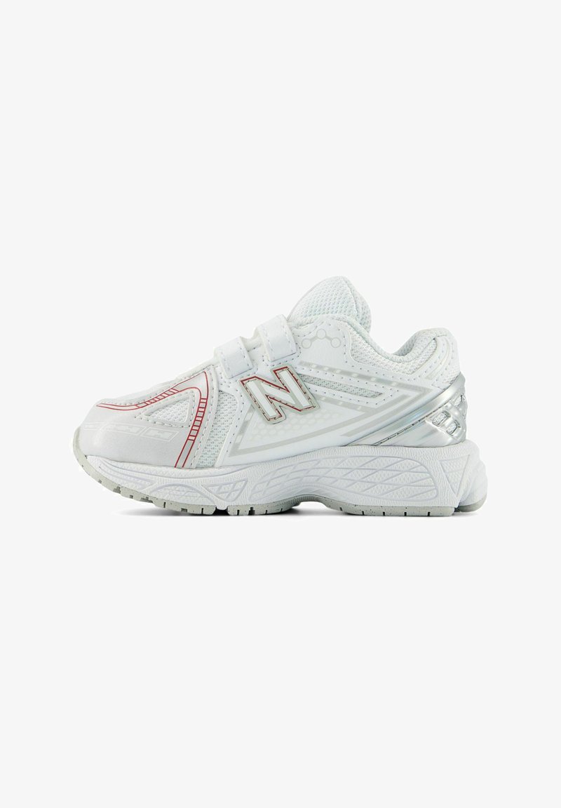 Baskets de sport blanches avec fermetures à scratch, tige en mesh, accents rouges et argentés, et semelle épaisse texturée, vue de profil.