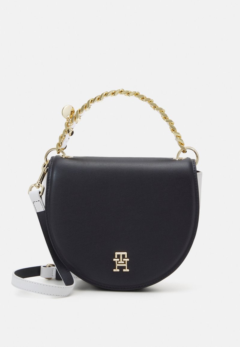 Sac à bandoulière en cuir noir avec une poignée chaîne dorée, des accents argentés et une forme courbée. Présente un logo doré à l'avant.