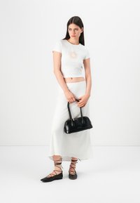 White cropped shirt with sun graphic, light gray skirt, black flat shoes with lace-up details, and black handbag. Simple and clean design.