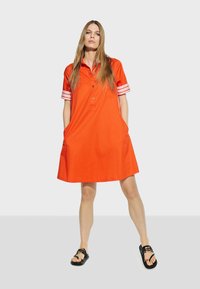 Abito in cotone rosso con maniche corte, caratterizzato da dettagli a righe bianche, colletto, chiusura con bottoni e tasche laterali.