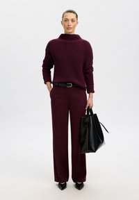 Pull enoraud à côtes avec col montant ; pantalon large assorti ; sac fourre-tout en cuir noir ; talons aiguilles noirs ; texture lisse.