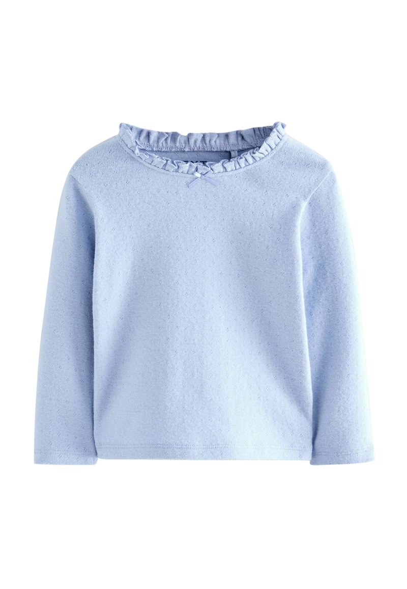 Top azzurro chiaro a maniche lunghe realizzato in tessuto morbido, con un collo a volant e un piccolo fiocco sotto. Superficie testurizzata con un motivo sottile.