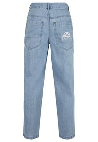 Jasnoniebieskie jeansy z denimu widziane od tyłu z dwoma kieszeniami, z których jedna ma haftowaną białą tęczę i napis „SOUTHPOLE“.