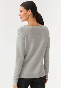 Grå langærmet sweater med en afslappet pasform, ribbet kant og rund halsudskæring. Blød strik med en sømløs bagsidedesign.
