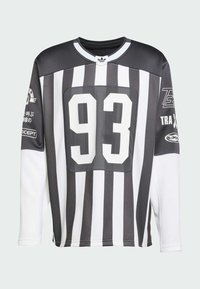 Mustvalge pikkade varrukatega jersy, millel on horisontaalsed triibud, ning mis sisaldab suurt '93' ja erinevaid logosid varrukatel. Kerge materjal, sportlik lõike.