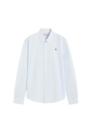 Camisa azul claro de manga larga con botones, con sutiles rayas verticales y un pequeño logo negro de calavera en el pecho izquierdo.