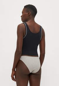 Svart tettsittende tank topp med hvit kant og grå sømløse undertøy. Glatt stoff med en nær-kroppen passform, som viser et enkelt design.