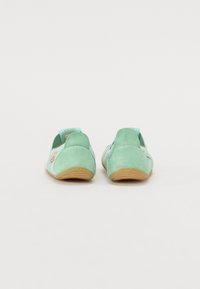 Mentazöld velúr slip-on cipők texturált talppal, kerek orral és rugalmas részletekkel a sarkán. Egyszerű dizájn, kontrasztos anyaggal.