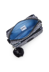 Kipling-väska med ett geometriskt svart och vitt mönster, dragkedjestängning, blå insida och en svart pom-pom nyckelringsaccessoar.