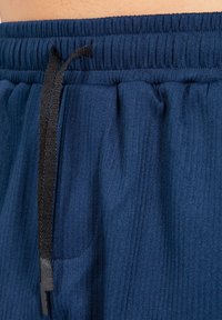 Pantalones cortos deportivos de color azul marino con una textura acanalada, cinturilla elástica y un cordón negro. Incluye bolsillos laterales para mayor funcionalidad.