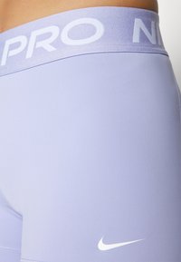 Lavender athletic shorts with a white "PRO" waistband and small white Nike swoosh logo. Smooth, stretchy fabric, close-fitting design.