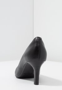 Czarna skórzana szpilka z wąskim noskiem, teksturowanym wykończeniem i smukłym obcasem. Posiada gładką sylwetkę i subtelne detale w szwie.