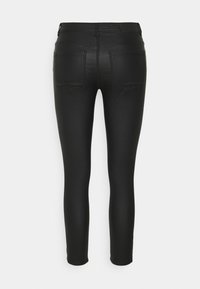 Jean ajustado negro de tela elástica. Presenta una cintura de media altura, dos bolsillos traseros y un acabado suave. Ajuste entallado en toda su longitud.