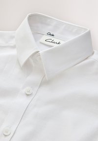 White button-up shirt with a structured collar and visible brand label reading "Clarks" inside the neckline.