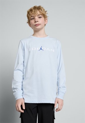 Hele sinine pika varrukaga särk, millel on valges kirjas "JORDAN" ja sinine Jumpmani logo. Omab ümmargust kaelust ja vabamat lõiget.