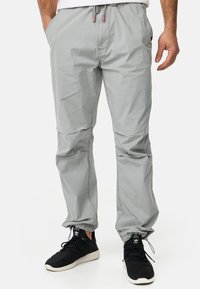 Pantalons gris clair, à taille élastique avec cordon de serrage, poches latérales et jambes fuselées. Tissu doux et léger, adapté pour une tenue décontractée.