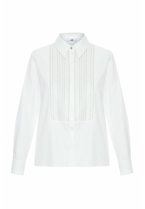 Camicia bianca con bottoni realizzata in tessuto morbido, dotata di pieghe verticali e delicati ricami decorativi lungo la parte frontale. Maniche lunghe con polsini abbottonati.