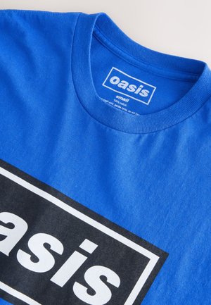 Maglietta di cotone blu con scollo rotondo, con una grafica rettangolare nera e il testo bianco "oasis" centrato sul davanti.