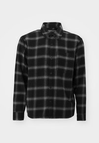 Svart rutigt flanellskjorta med grå rutig mönster, knäppning fram, krage, långa ärmar och en enda bröstficka. Mjuk textur.
