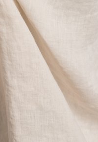 Hellbeige Leinenstoff mit einer weichen, strukturierten Oberfläche, der eine lockere Webart aufweist, die ein natürliches, luftiges Aussehen erzeugt.