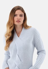 Hellblaues Strickpullover mit Wickeldesign, tiefem Ausschnitt und strukturiertem Muster. Lange Ärmel und eine bequeme, lockere Passform.